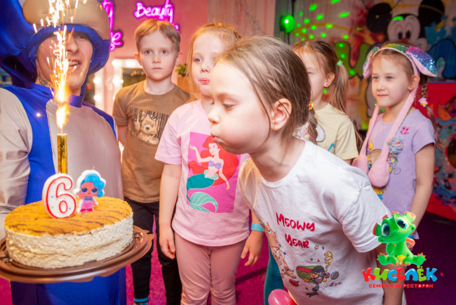 Девочка задувает торт